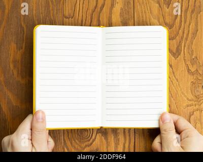 Hands open empty notebook on wooden desk. top view, copy space Stock Photo