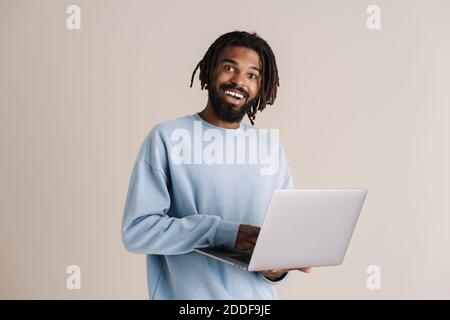 Happy african american guy smiling and typing on laptop isolated over white background Stock Photo