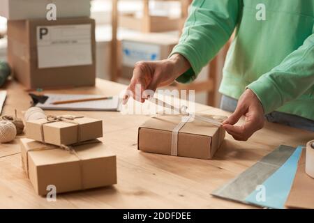 Close-up of woman standing at the table and decorating gift boxes with ribbons to holiday Stock Photo