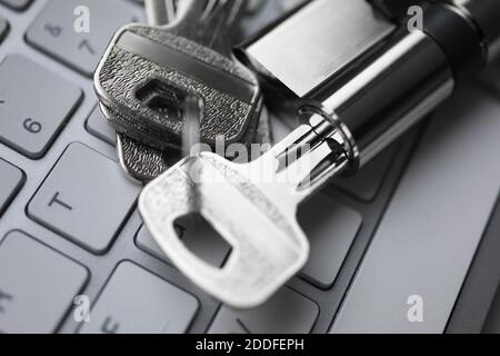Silver key with lock lie on white keyboard closeup backround. Stock Photo