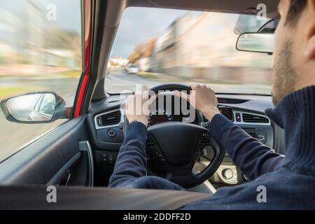 Young man is driving a car in city. Fast driving. View from interior. Stock Photo