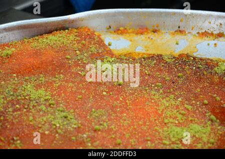 Kanafeh, traditional Middle Eastern dessert made with cheese, in a  siniyyeh large metal tray. Amman, Jordan Stock Photo