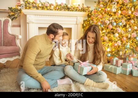 Young family feeeling happy opening christmas gifts Stock Photo