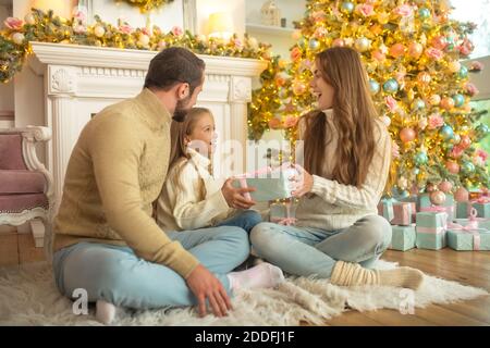 Young family feeeling happy opening christmas gifts Stock Photo