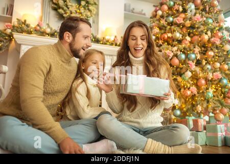 Young family feeeling happy opening christmas gifts Stock Photo