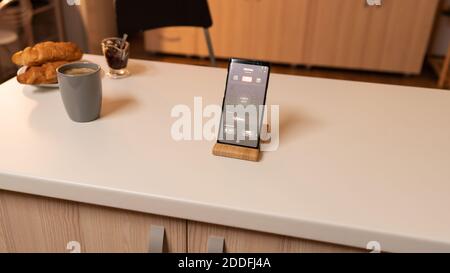 Managing interior home lighting with mobile device. Phone with touching screen late at night with technology to change lights in home. Stock Photo