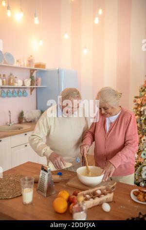 Elderly couple cooking something in the kitchen and looking involved Stock Photo