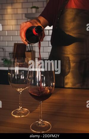 A man pours red wine into a glass Stock Photo