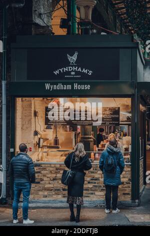 London, UK - November 19, 2020: People socially distanced queuing at a Wyndham take away food stall in Borough Market, one of the largest and oldest f Stock Photo