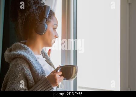 A young Latina female in wireless headphones and drinking coffee Stock Photo