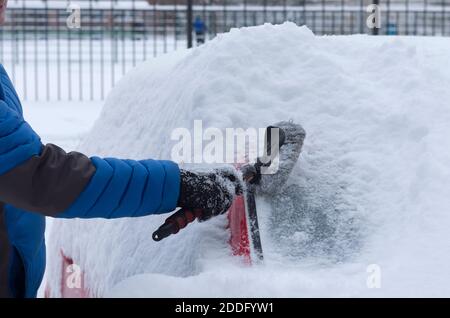 Man's hand cleans the car from fresh snow with a brush Stock Photo