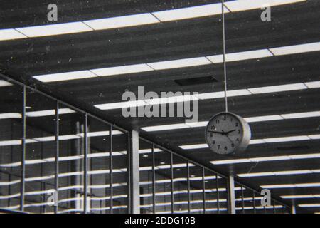 Fine 1970s vintage black and white photography of a clock hanging in a large hallway. Stock Photo