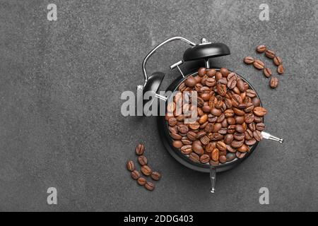 Alarm clock with coffee beans on dark background Stock Photo