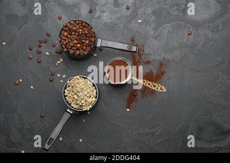 Green and roasted coffee beans with powder on dark background Stock Photo
