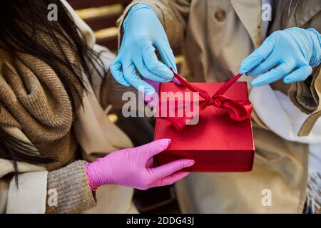 Female friends on sterile gloves opening present on the street Stock Photo