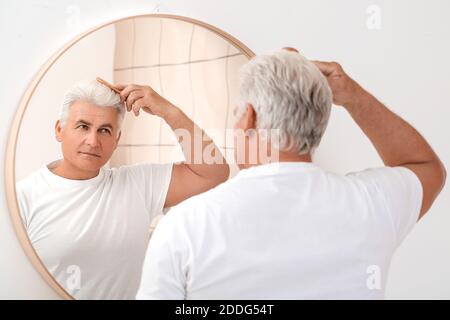 Senior man combing his hair near mirror Stock Photo