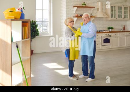 Happy mature romantic couple standing and dancing after cleaning home together Stock Photo
