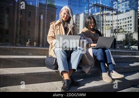 Elegant women working on laptops on the street Stock Photo