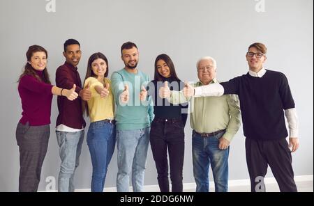 Group of happy diverse people standing together, giving thumbs-up and looking at camera Stock Photo