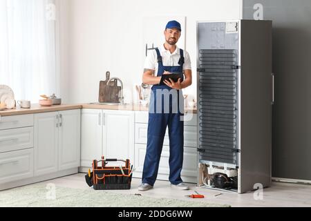 Worker repairing fridge in kitchen Stock Photo