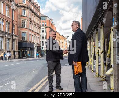 two men shake hands in the street, northern quarter manchester Stock Photo