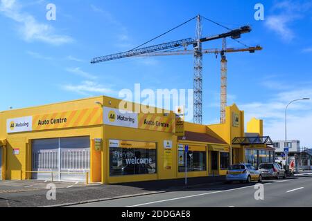 The AA (Automobile Association) building in Tauranga, New Zealand, with two construction cranes at work in the background Stock Photo