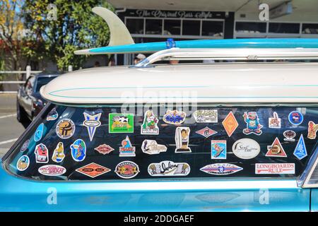 A surfboard and many surfing-related stickers on the back of a classic 1960 Mercury Commuter. Photographed at a car show in Tauranga, New Zealand Stock Photo