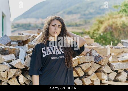 Portrait of young woman with long hair, by log pile Stock Photo