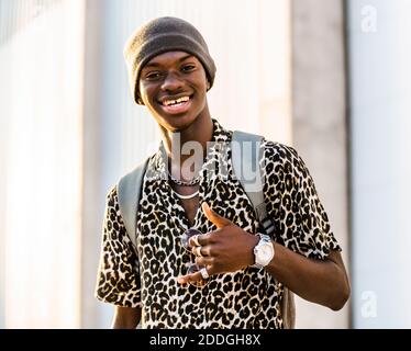 Content handsome African American male in trendy clothing showing thumb up while looking at camera and smiling Stock Photo