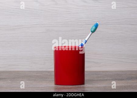 blue toothbrush in a red mug in a bathroom Stock Photo