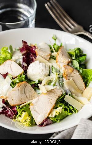 High angle closeup of delicious Caesar salad with chicken and vegetables served on table in cafe Stock Photo