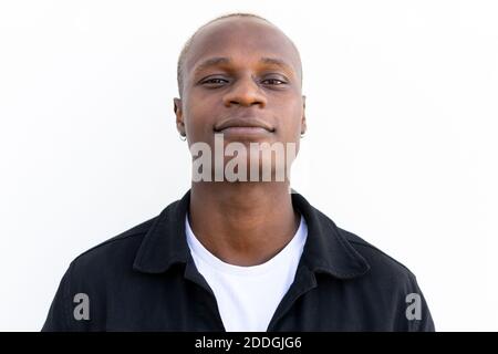 Satisfied African American male in casual outfit smiling and looking at camera on white background Stock Photo
