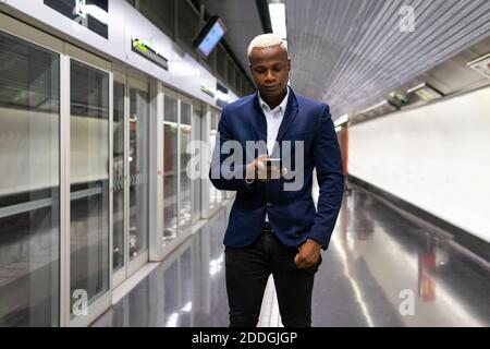 African American businessman standing in subway train and messaging on smartphone while commuting to work Stock Photo