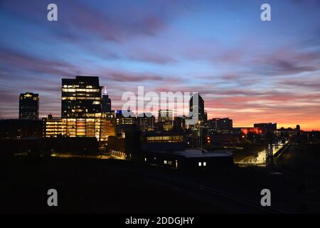 The city lights are still on as the sun rises to the east and paints the clouds orange during sunrise over downtown Raleigh North Carolina Stock Photo