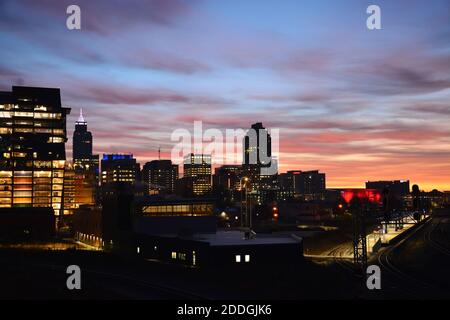 The city lights are still on as the sun rises to the east and paints the clouds orange during sunrise over downtown Raleigh North Carolina Stock Photo