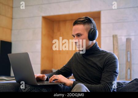 Young businessman in headphones having video call via netbook at hotel lobby Stock Photo