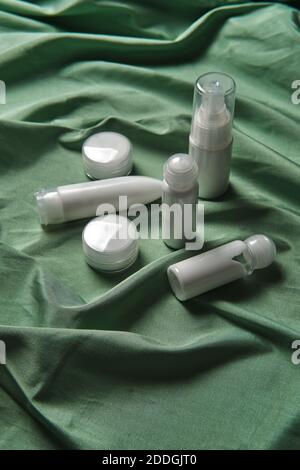 High angle of assorted plastic bottles and jars of skincare products arranged on green fabric background Stock Photo