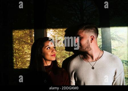Cheerful man and smiling Woman looking at each other while standing in apartment lit by sunlight Stock Photo