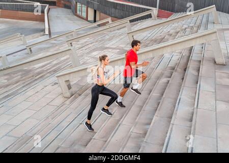From above side view of couple of runners in sportswear jogging on staircase while working out in town Stock Photo