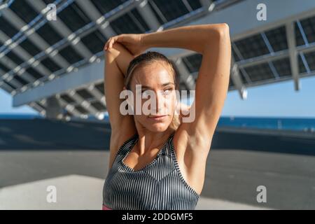Charming female runner stretching arms while warming up before training and looking away Stock Photo