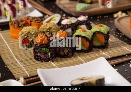From above of arrangement of delicious veggie rolls on plates and bamboo mat on table in cafe Stock Photo