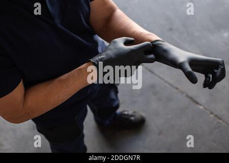 From above anonymous male employee putting on latex gloves during work in garage Stock Photo