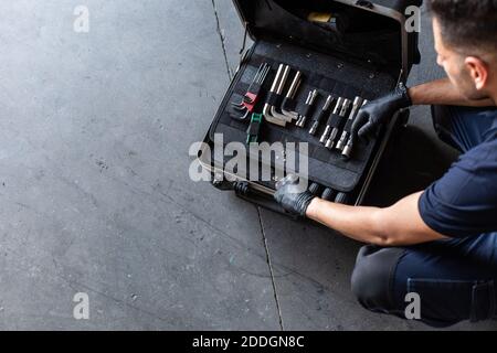 From above male technician picking screwdriver bits from tool box while working in garage Stock Photo