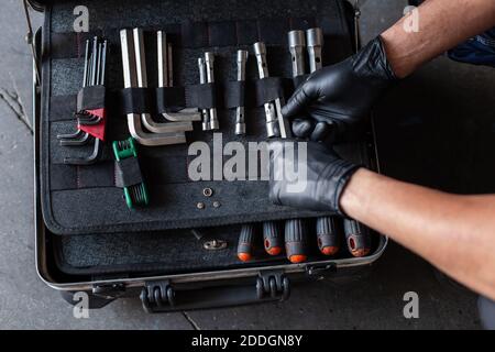 From above unrecognizable male technician picking screwdriver bits from tool box while working in garage Stock Photo