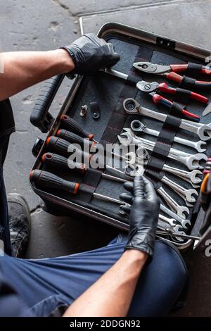 From above unrecognizable male technician picking screwdriver bits from tool box while working in garage Stock Photo
