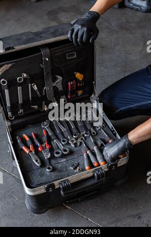 From above unrecognizable male technician picking screwdriver bits from tool box while working in garage Stock Photo