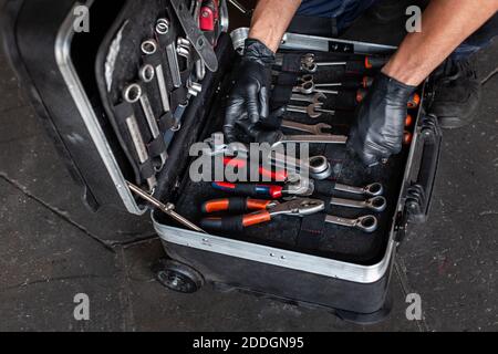 From above unrecognizable male technician picking screwdriver bits from tool box while working in garage Stock Photo
