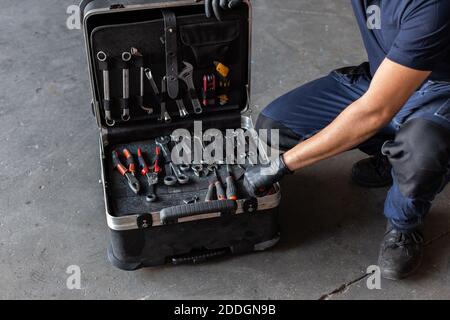 From above unrecognizable male technician picking screwdriver bits from tool box while working in garage Stock Photo
