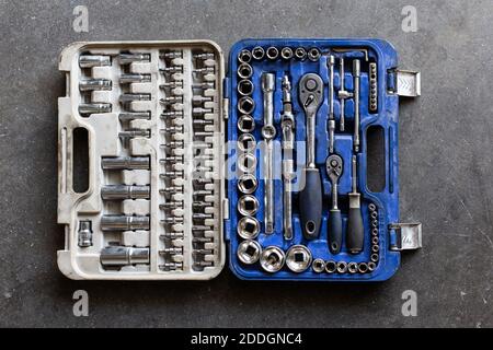 Top view of kit of metal wrenches and bits placed inside plastic box on garage floor Stock Photo