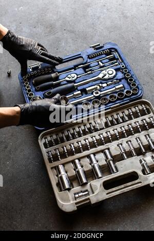 From above anonymous male technician in latex gloves selecting wrench bit from tool box during work in garage Stock Photo